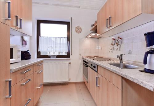 eine Küche mit Holzschränken, einem Waschbecken und einem Fenster in der Unterkunft Ferienwohnung Brinkmann 4**** mit Moselblick in Dieblich