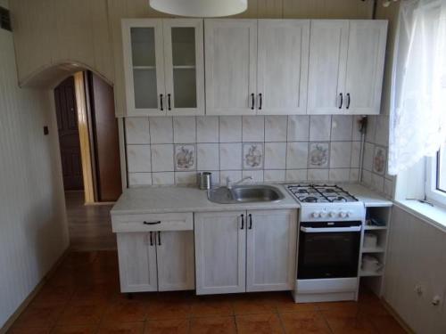 a kitchen with white cabinets and a sink and a stove at Walecznych 11 in Gdańsk