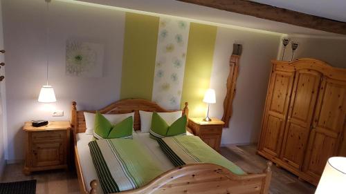 a bedroom with a wooden bed with green pillows at Gästezimmer Vockerodt in Nottleben