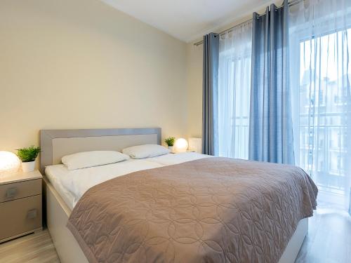 sypialnia z dużym łóżkiem i dużym oknem w obiekcie VacationClub – Stella Baltic Apartament 37 w Świnoujściu