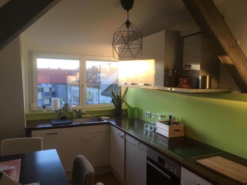 a kitchen with green walls and a large window at Fair Messe Rooftop Loft in Nürnberg in Nuremberg