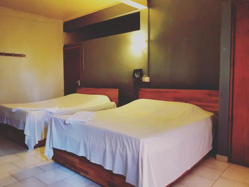 two beds in a hotel room with white sheets at Mountview Tourist Residence in Quatre Bornes