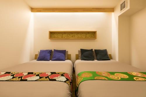 two beds sitting next to each other in a room at Guesthouse Raku in Kyoto