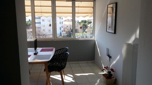 ein Esszimmer mit einem Tisch, 2 Stühlen und 2 Fenstern in der Unterkunft Athenian Luxury apartment, near metro station Chalandri, Nu 2 in Athen