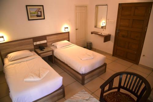 a hotel room with two beds and a mirror at RAMAS GARDEN in Trivandrum