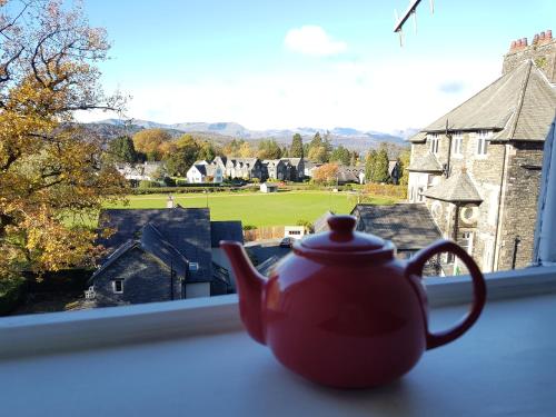 Archway Guest House في ويندرمير: وعاء الشاي الأحمر موجود على حافة النافذة