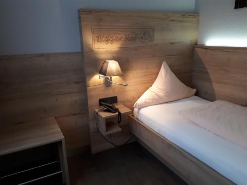 a small bedroom with a bed and a lamp at Hotel Bigger Hof - Wirtshaus Platzhirsch am Jahnplatz in Olsberg