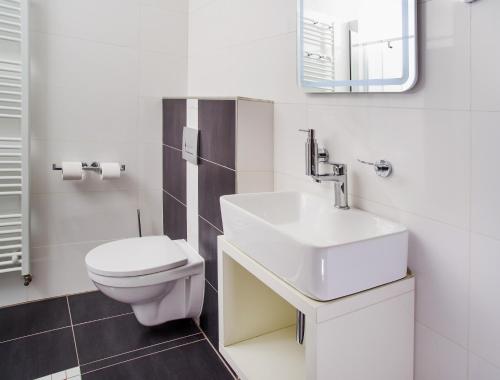 a white bathroom with a sink and a toilet at Penzion Lesni in Milovice