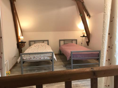 2 letti in una camera con pavimento in legno di Le gîte du Canal des Ardennes a Le Chesne