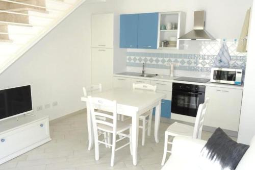 eine weiße Küche mit einem weißen Tisch und Stühlen in der Unterkunft Romantica casa al mare con piscina in Sardegna in Viddalba