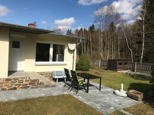 a patio with a table and chairs next to a house at Ferienbungalow Grünbach in Grünbach