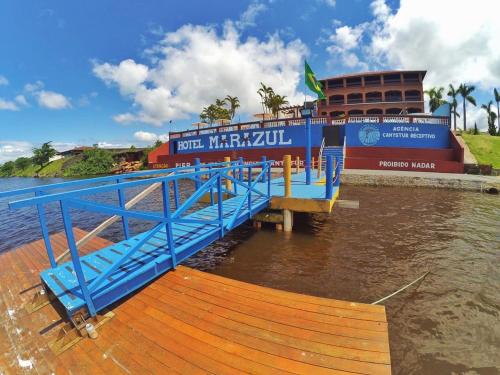 a blue dock in the water next to a building at Hotel Marazul in Cananéia