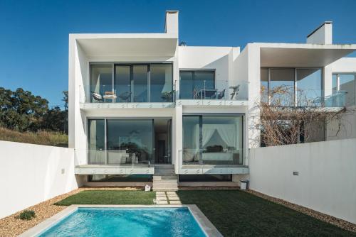 a white house with a swimming pool in front of it at VillaMar in Sesimbra