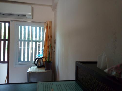 a living room with a window and a table with a keyboard at Charlee House in Trang