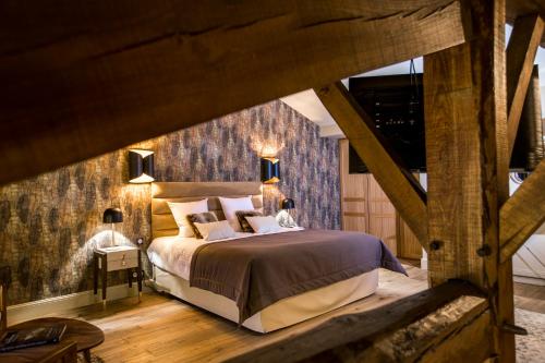 a bedroom with a large bed and a wooden wall at Hotel Clos Castel in Casteljaloux