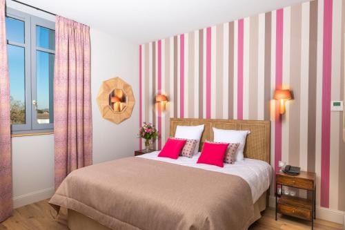 a bedroom with a large bed with pink pillows at Hotel Clos Castel Villas Spa in Casteljaloux