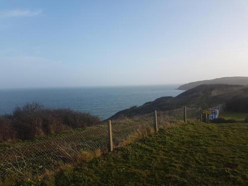 a fence on a hill next to the ocean at Springfield B6 in Brixham