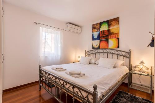 a bedroom with a metal bed with a painting on the wall at Apartments and Rooms Villa Erede in Split