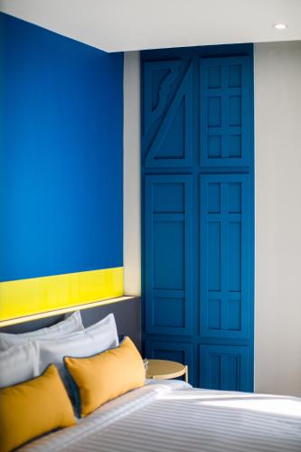 a bedroom with a blue door and a bed with yellow pillows at Hotel Tranz in Bangkok