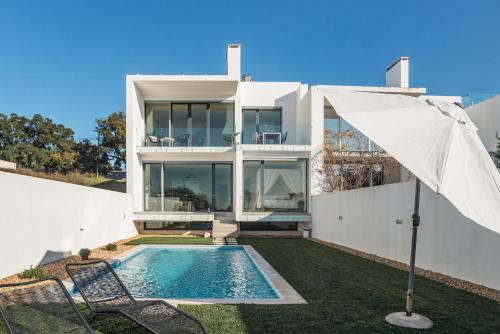 a house with a swimming pool and an umbrella at Lemon Tree Home in Sesimbra