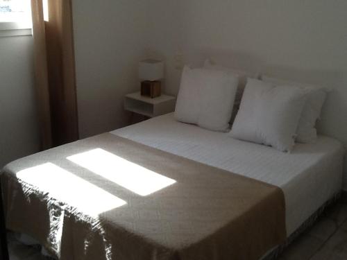 une chambre avec un lit avec des draps blancs et des oreillers dans l'établissement 10 Casa scaledda 3 étoiles, à Porto-Vecchio