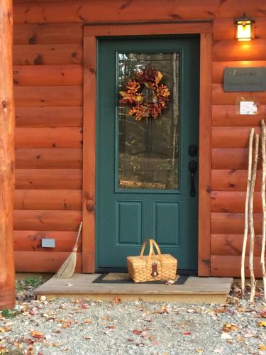a green door on a house with a wreath on it at Robert Frost Mountain Cabins in Middlebury