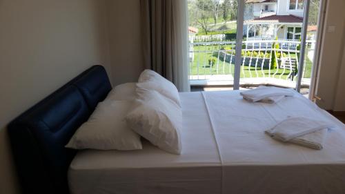 a bed with white sheets and pillows and a window at PALACE KIRKPINAR in Sakarya