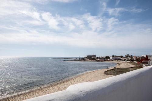 a beach with a white fence and the ocean at Villa Layla on the beach in Torre Lapillo