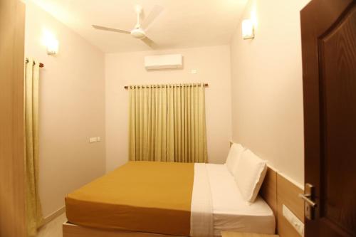 a small bedroom with a bed and a ceiling fan at Castilo Inn Hotel Apartments in Cochin