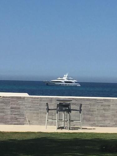 a bench and a boat in the ocean with a yacht at SUITEBEACH b&b and resort in Marsala