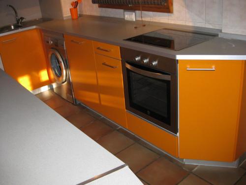 uma cozinha laranja com um fogão e uma máquina de lavar louça em Casa Artigot em Gea de Albarracín