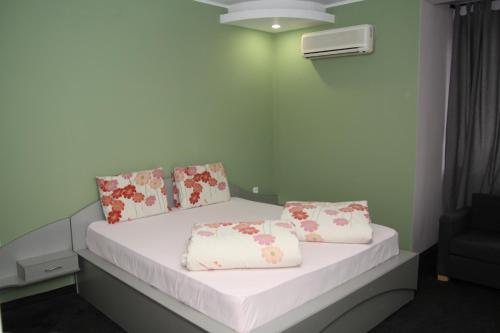 a bedroom with a bed with white sheets and floral pillows at Hotel Color in Asenovgrad