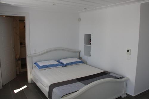 a white bedroom with a bed with two pillows at Andoni's House in Pitrofós
