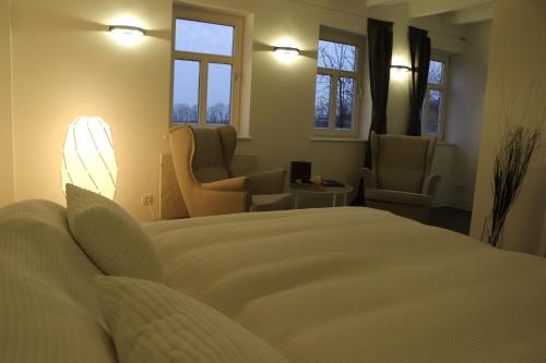 a bedroom with a bed and two chairs and windows at "Fahner Mühle" in Gierstädt
