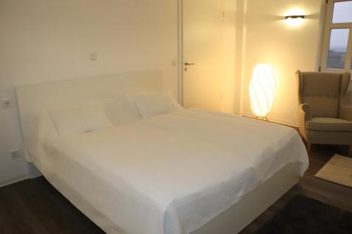 a bedroom with a white bed and a chair at "Fahner Mühle" in Gierstädt