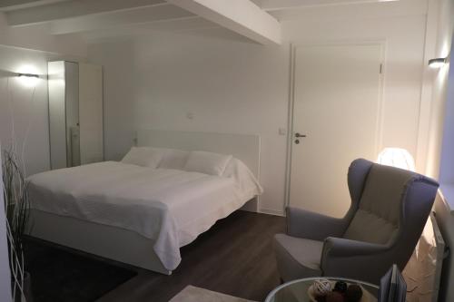 a small bedroom with a bed and a chair at "Fahner Mühle" in Gierstädt