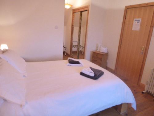 a bedroom with a white bed with two towels on it at Dacama House in Ullapool