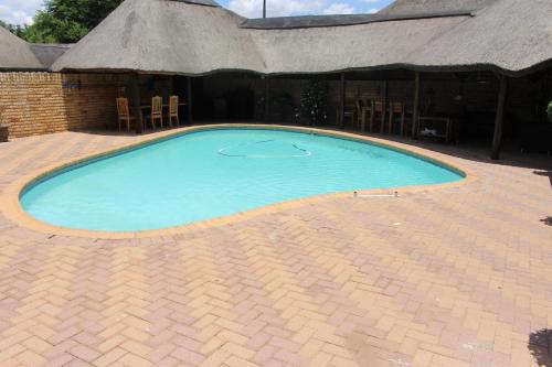 a large swimming pool with chairs and a building at The Willow Tree Guesthouse in Klerksdorp