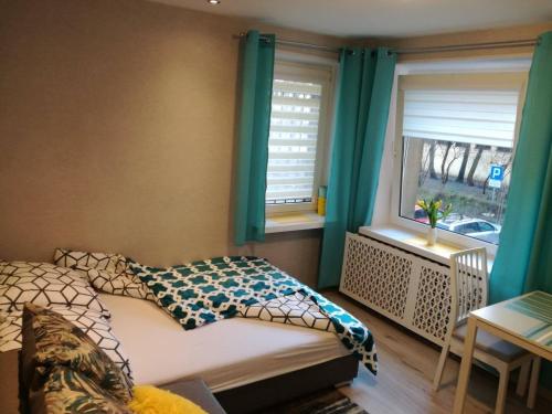 a bedroom with a bed and two windows with green curtains at Kremerowska Apartment in Krakow