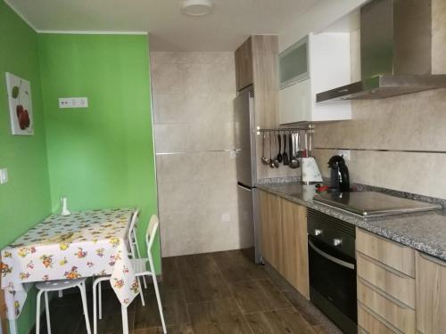 uma cozinha com uma mesa e uma parede verde em Casa rural Camelle Casa dos avós em Camariñas