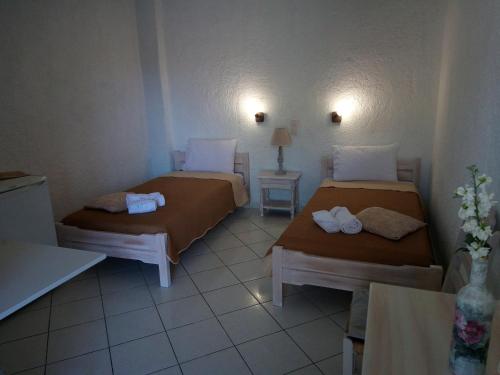 a room with two beds and a table with a lamp at Εmmi in Koutsounari