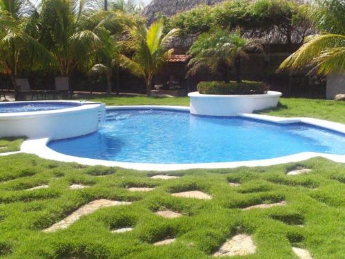 a small pool in a yard with grass and palm trees at Solyar Luxury Spanish Beachfront Home in Pochomil