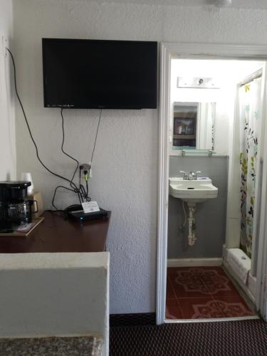 a bathroom with a sink and a television on the wall at Budget Inn Hamilton in Hamilton