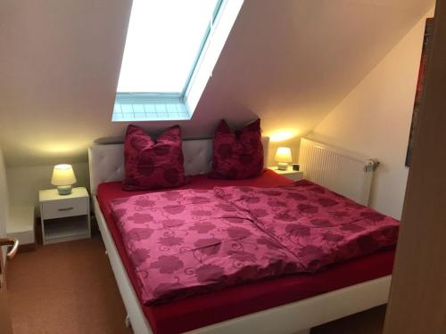 a bedroom with a bed with pink sheets and a window at Ferienwohnung mit Whirlpool in Ihlienworth