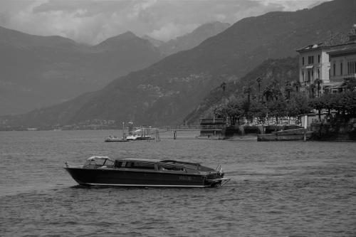 a boat in the water with mountains in the background at Bellagio Love apartment Pool Near lake Free parking in Bellagio
