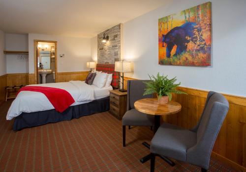 a hotel room with a bed and a table and chairs at Bear Hill Lodge in Jasper