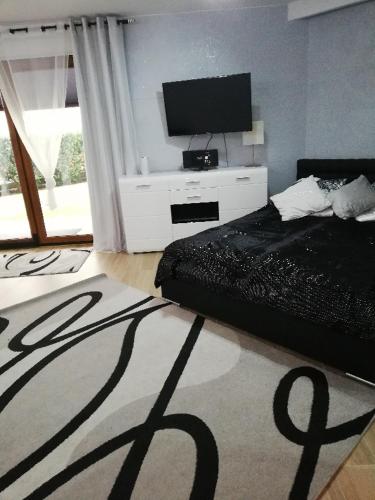 a bedroom with a bed and a flat screen tv at Apartament Superior Maloves Władysławowo in Władysławowo