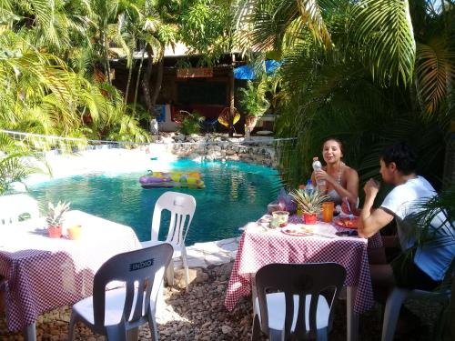 a group of people sitting at tables by a pool at Tower Bridge Hostel in Puerto Escondido