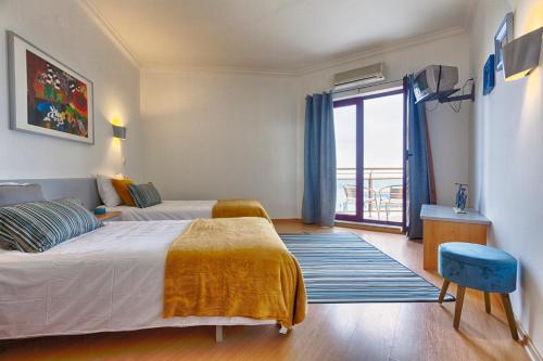 a hotel room with two beds and a balcony at Beachtour Lux Sunset - Ericeira in Ericeira