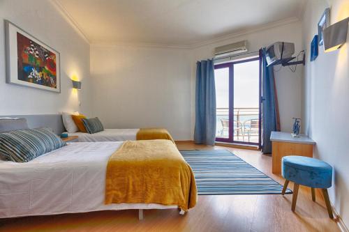 a hotel room with two beds and a balcony at T2 Apt-Beachtour Lux Sunset - Ericeira in Ericeira